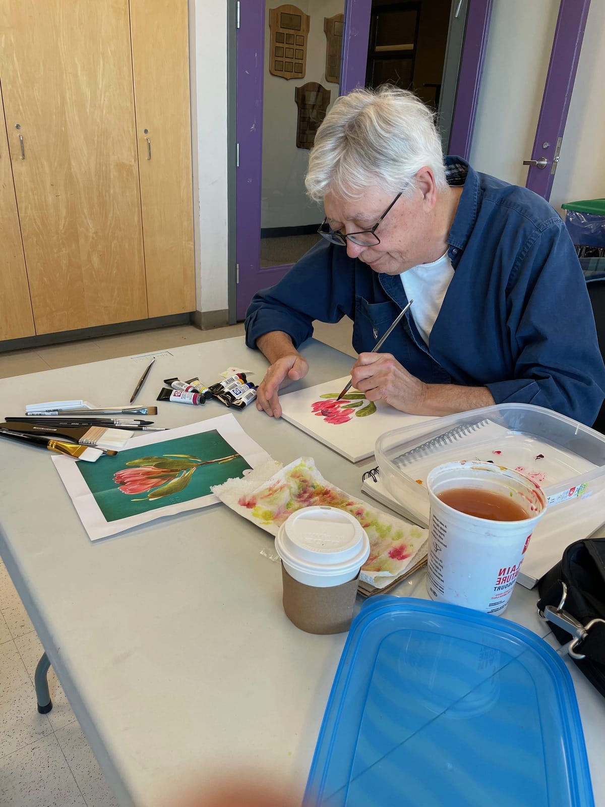 woman painting a water colour flower in an art class