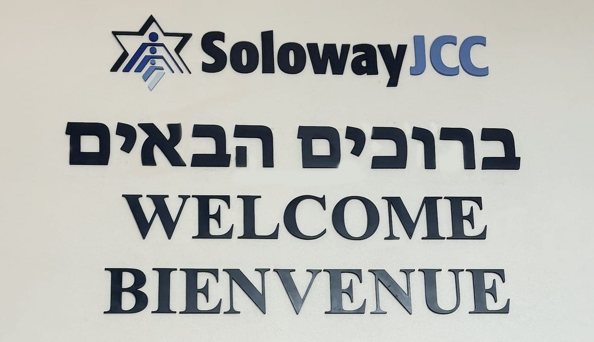 The sign in the front lobby saying welcome in english, french, and hebrew.
