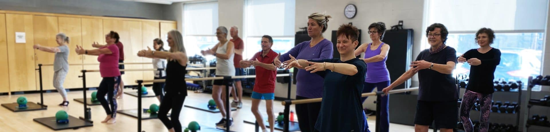 A group of people doing a ballet barre exercise class