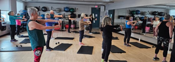 People at a group fitness class, exercising.